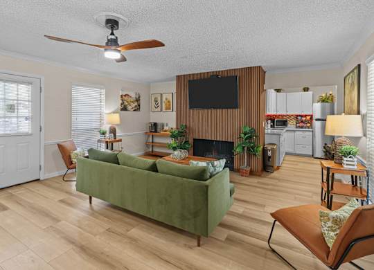 a living room with a green couch and a ceiling fan