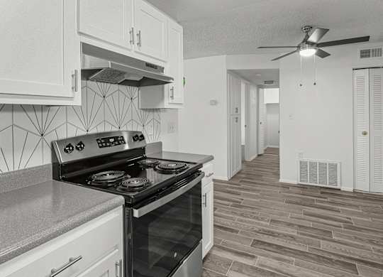 an empty kitchen with white cabinets and a black stove