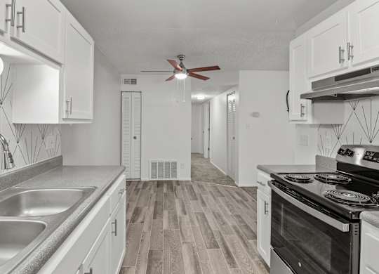 an empty kitchen with white cabinets and stainless steel appliances and a ceiling fan