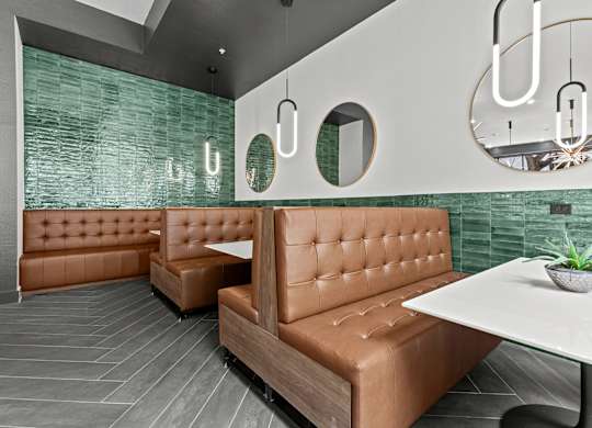 A modern dining area with a white table and brown booths.