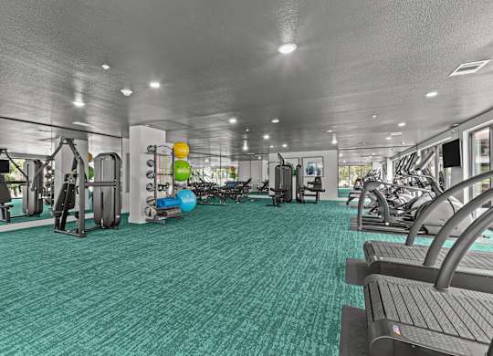 A gym with a variety of equipment including treadmills, weights, and exercise machines.