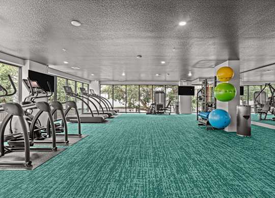 A gym with a green carpet and various exercise equipment.