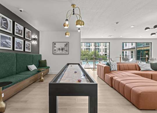 A billiard table is in the middle of a room with a green sofa and a brown sofa.