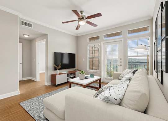 A living room with a couch, a television, and a ceiling fan.