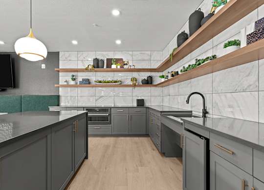 A modern kitchen with dark grey cabinets and a wooden shelf above the counter.