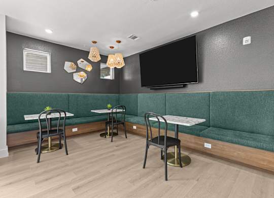 A room with a green couch and a television on the wall.