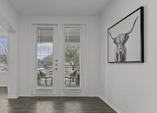 A black and white painting of a bull head hangs on a white wall above a white door.
