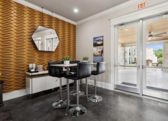 A room with a wooden wall and a mirror above a table with chairs.