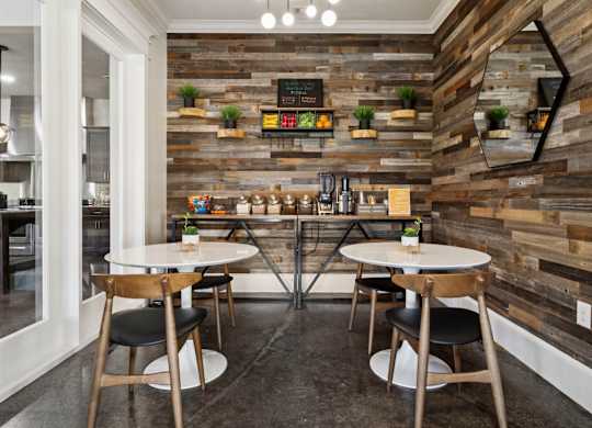 A modern dining area with wooden walls and tables set for two.