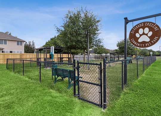 A sign for a community pet park is displayed on a fence.