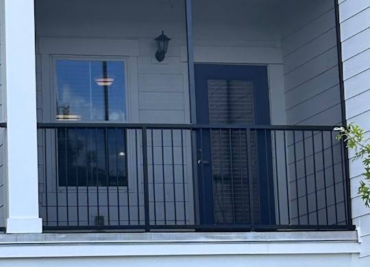 A balcony with a black railing and a window.
