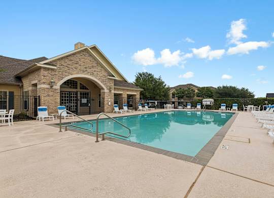 A large outdoor swimming pool with lounge chairs around it.