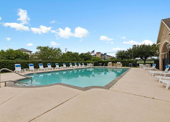 A large swimming pool with lounge chairs around it.