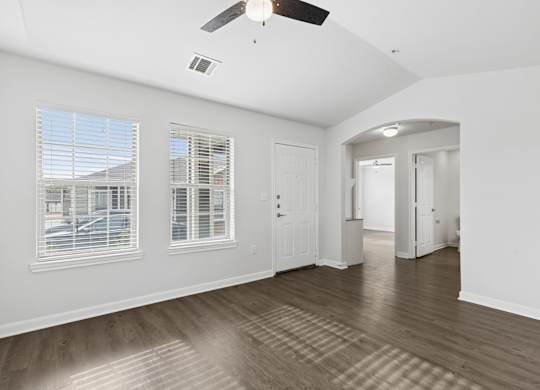A room with a ceiling fan and a view of a house through the window.
