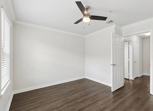 A room with a ceiling fan and wooden floors.