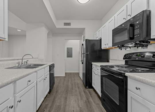 A kitchen with black appliances and white cabinets.