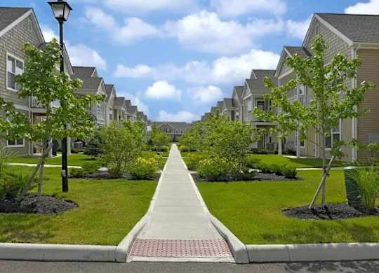 A row of houses with a sidewalk in the middle.