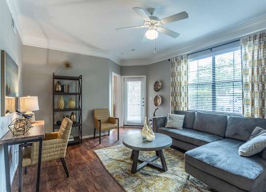 A living room with a grey couch, a wooden coffee table, and a ceiling fan.