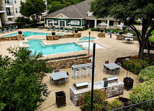an aerial view of a pool and patio with tables and umbrellas