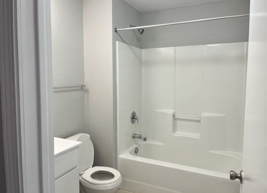 a white bathroom with a toilet and a tub and a sink