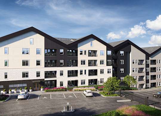 A modern apartment complex with a parking lot in front.