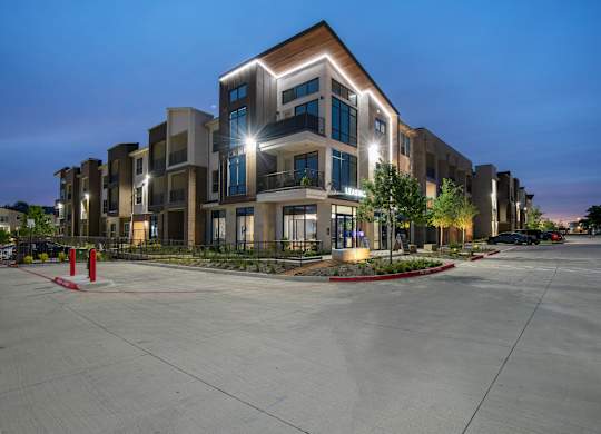 A modern apartment complex with a parking lot in front.