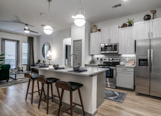 a kitchen with stainless steel appliances and a large island with three stools