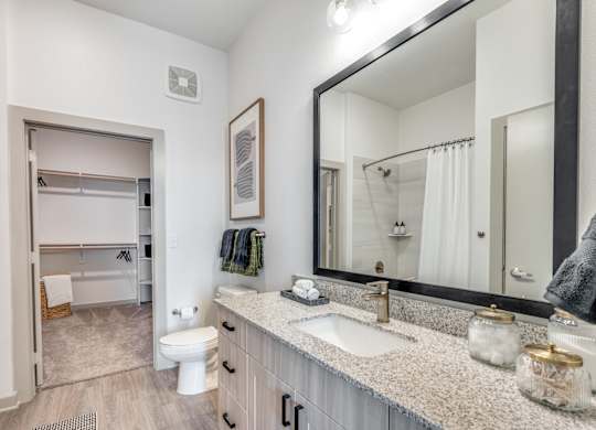 A bathroom with a white toilet, sink, and mirror.