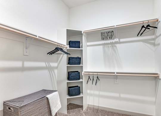 A white closet with clothes hanging and a brown box on the floor.
