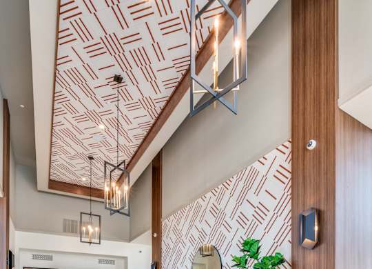 A living room with a patterned wallpaper and a wooden ceiling.