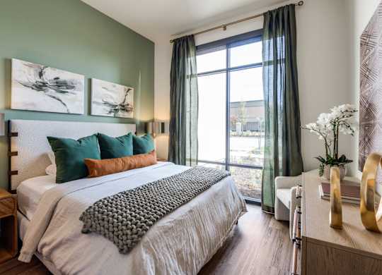 A bedroom with a large bed and a window with curtains.