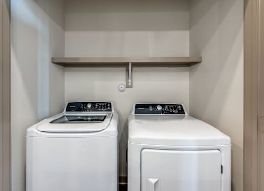 Two white front loading washing machines in a small laundry room.