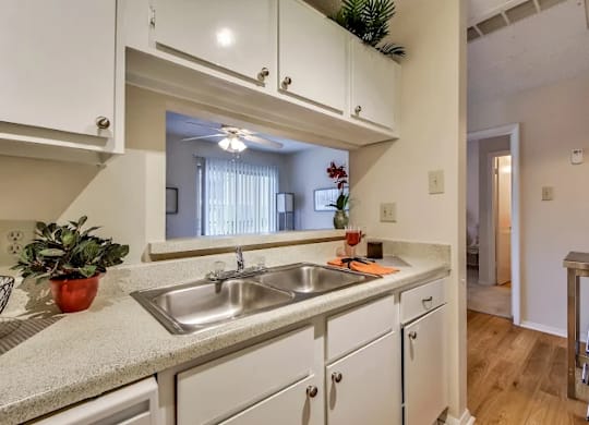 A kitchen with white cabinets and a stainless steel sink.