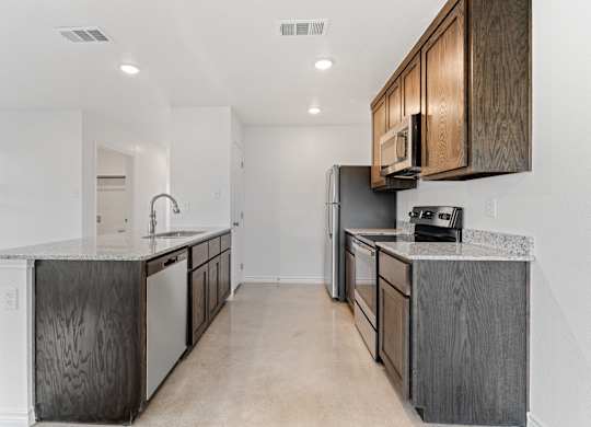 an empty kitchen with stainless steel appliances and wooden cabinets