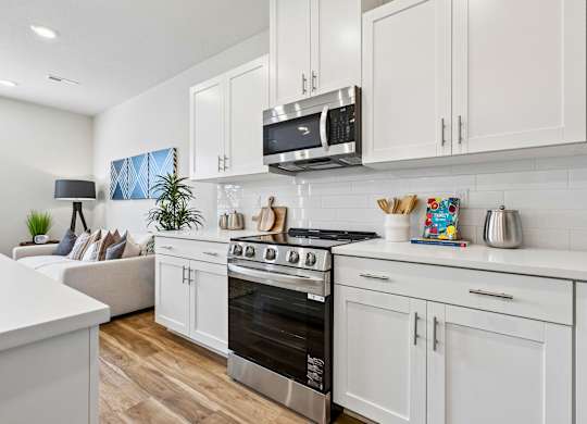 A modern kitchen with white cabinets and a black stove top.