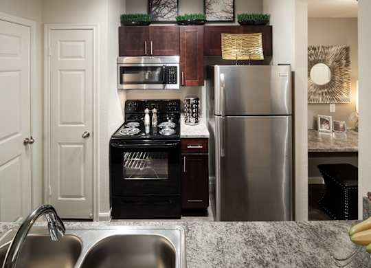 A modern kitchen with a stainless steel refrigerator, oven, and sink.