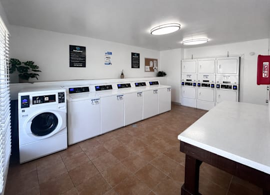 A laundry room with a white counter and brown tiles.