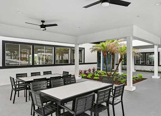 A patio with a table and chairs and a ceiling fan.