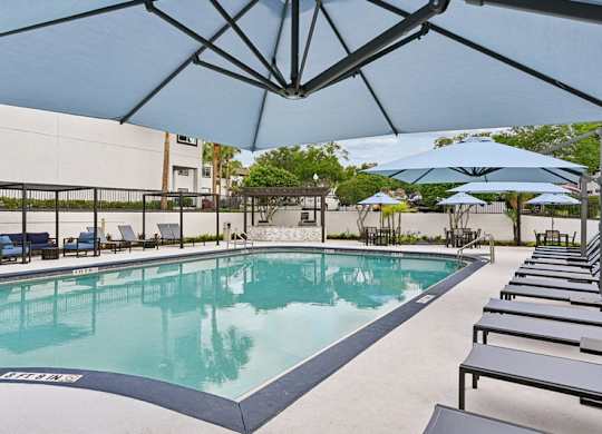 A large outdoor pool with sun loungers and umbrellas.