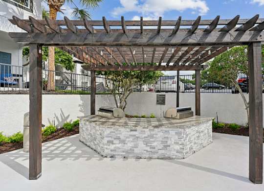 A wooden pergola is over a stone bench.