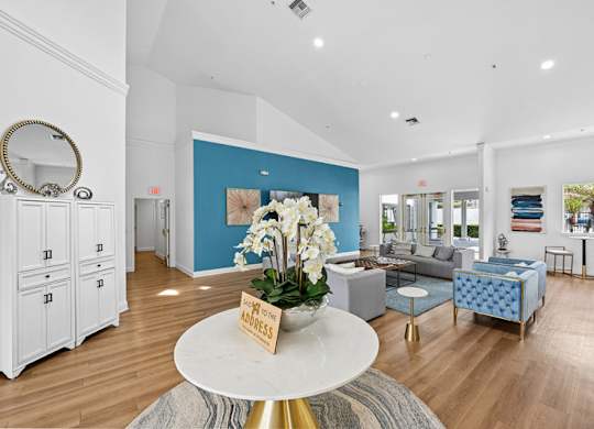 A living room with a white coffee table and a vase of white flowers on it.
