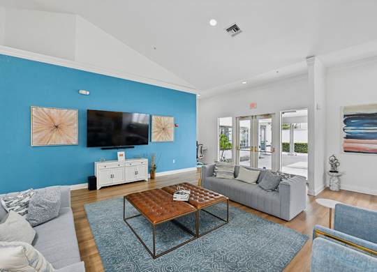 A living room with a grey couch, a wooden coffee table, and a blue wall.