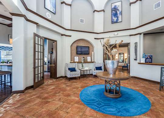 A large room with a blue rug and a wooden table.