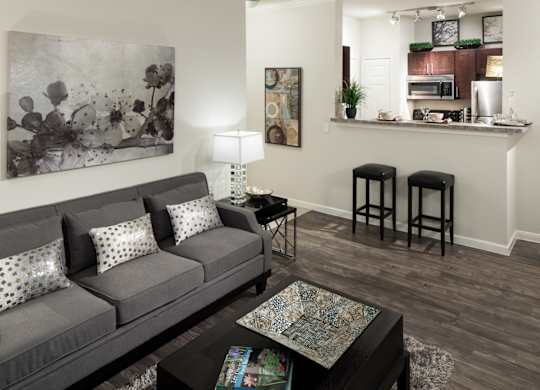 A grey couch with white pillows sits in a living room with a coffee table in front of it.
