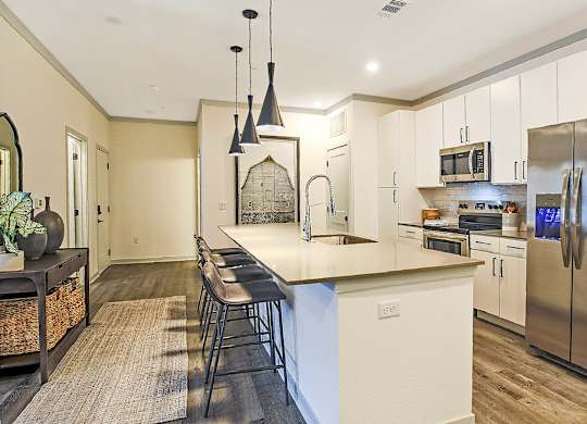 A kitchen with a white island and stainless steel appliances.