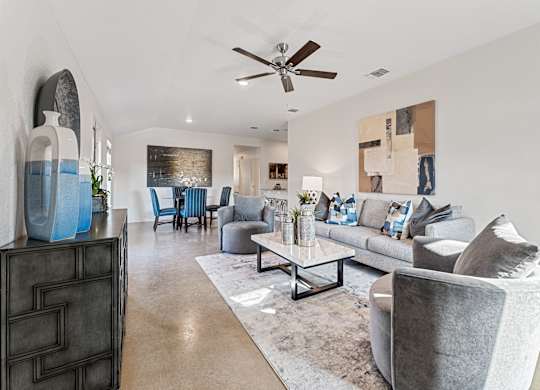 a living room with couches and chairs and a ceiling fan