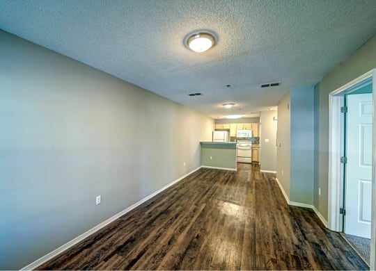a long hallway with a wood floor and a kitchen