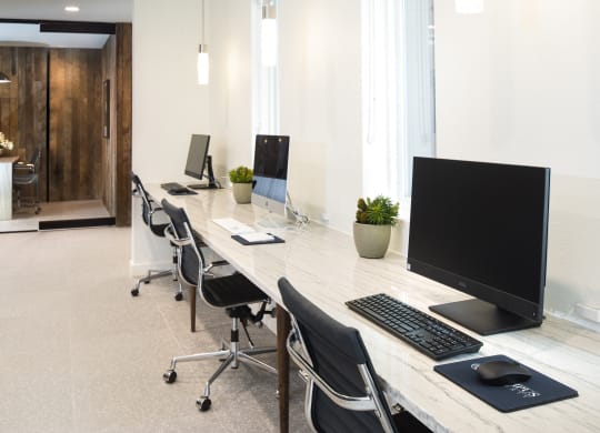 an office with a long desk with computers and chairs