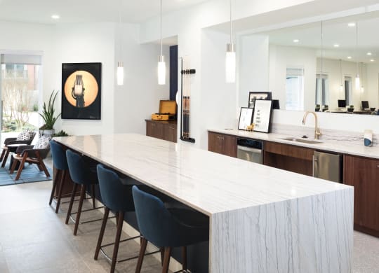 a large white kitchen with a long island and blue chairs
