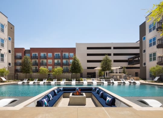 a swimming pool with lounge chairs in front of an apartment building
